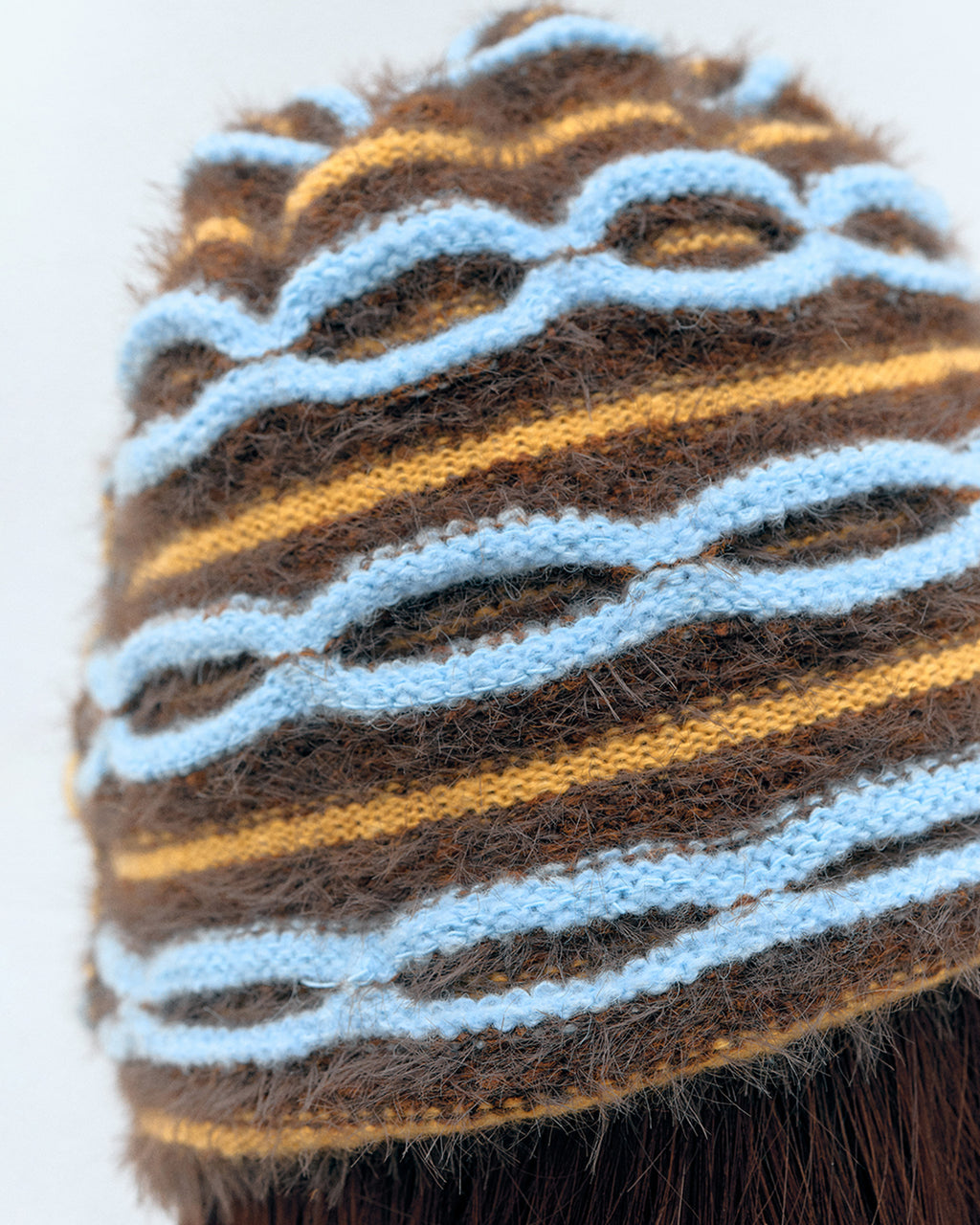 3d knit beanie with textured pattern worn on model
close-up of reversible knit beanie in brown and yellow stripes
side profile of wool mohair beanie with sculptural texture