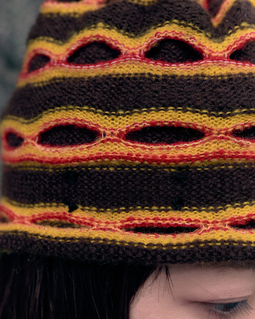 3d knit beanie with textured pattern worn on model
close-up of reversible knit beanie in brown and yellow stripes
side profile of wool mohair beanie with sculptural texture