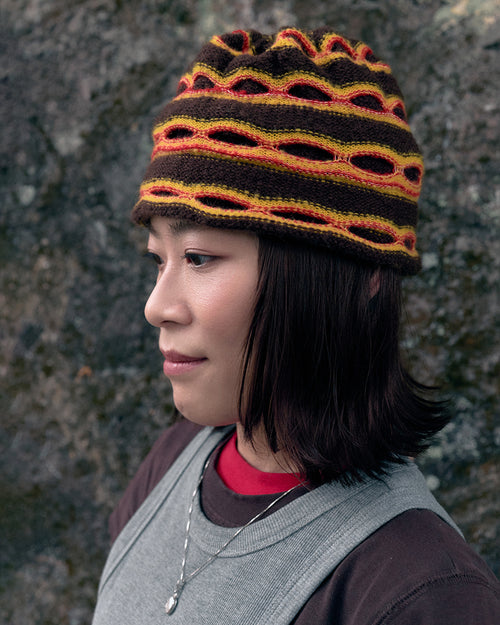 3d knit beanie with textured pattern worn on model
close-up of reversible knit beanie in brown and yellow stripes
side profile of wool mohair beanie with sculptural texture