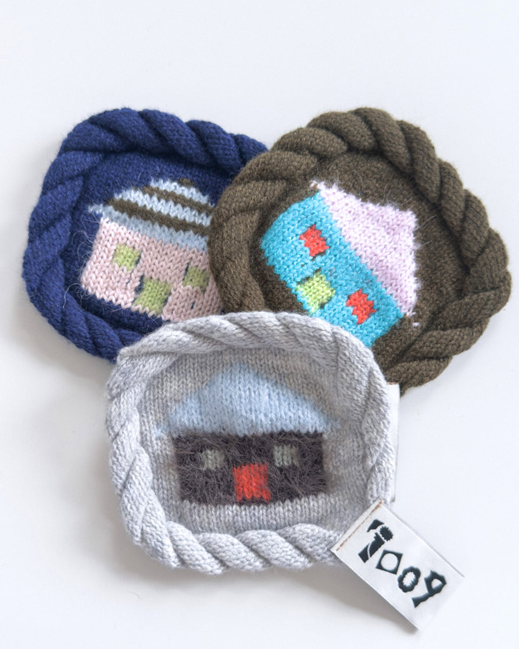 knit house coaster with colorful wool design and rope border
handmade wool coaster with house motif on white background
close-up of textured knit coaster with house pattern