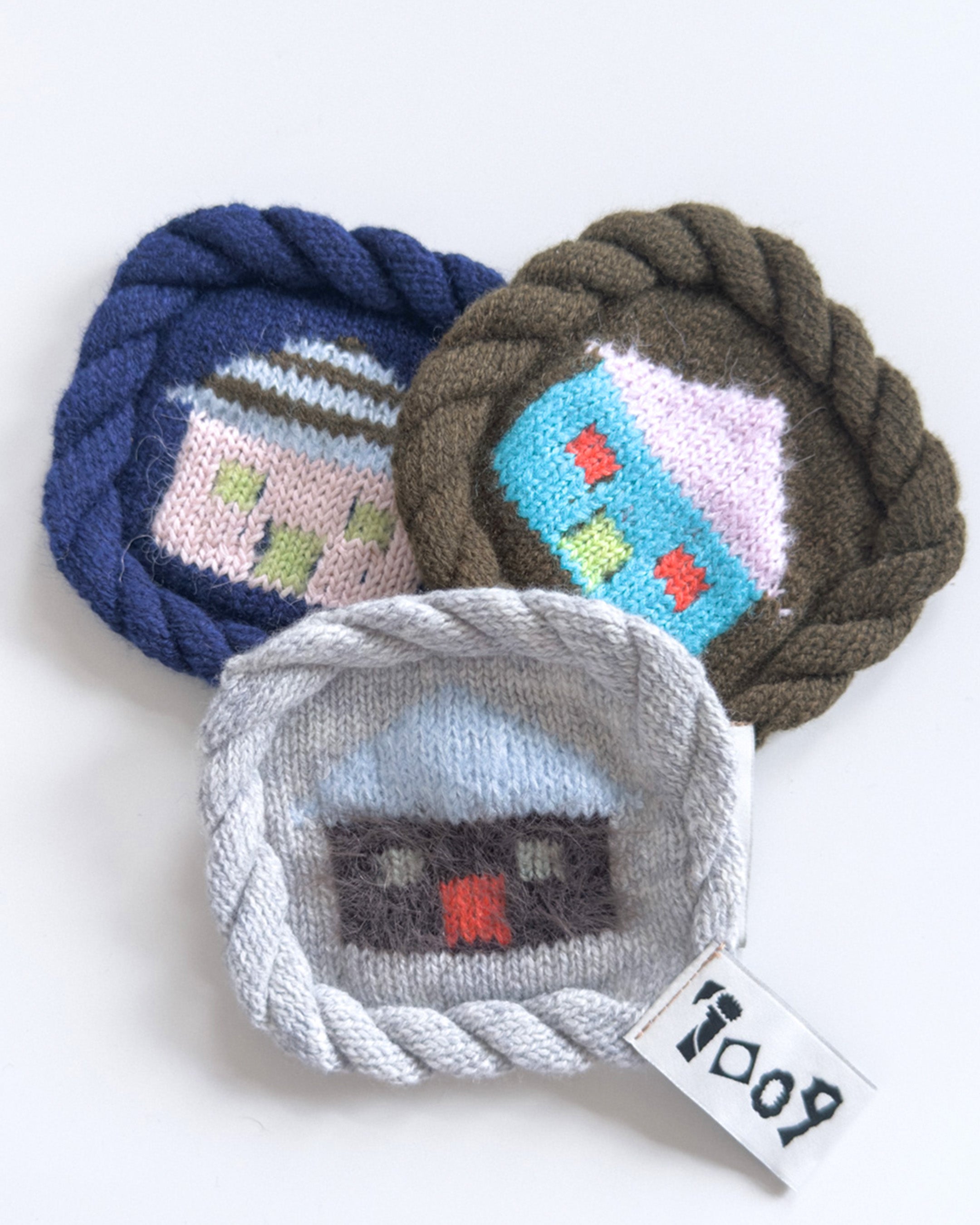 knit house coaster with colorful wool design and rope border
handmade wool coaster with house motif on white background
close-up of textured knit coaster with house pattern