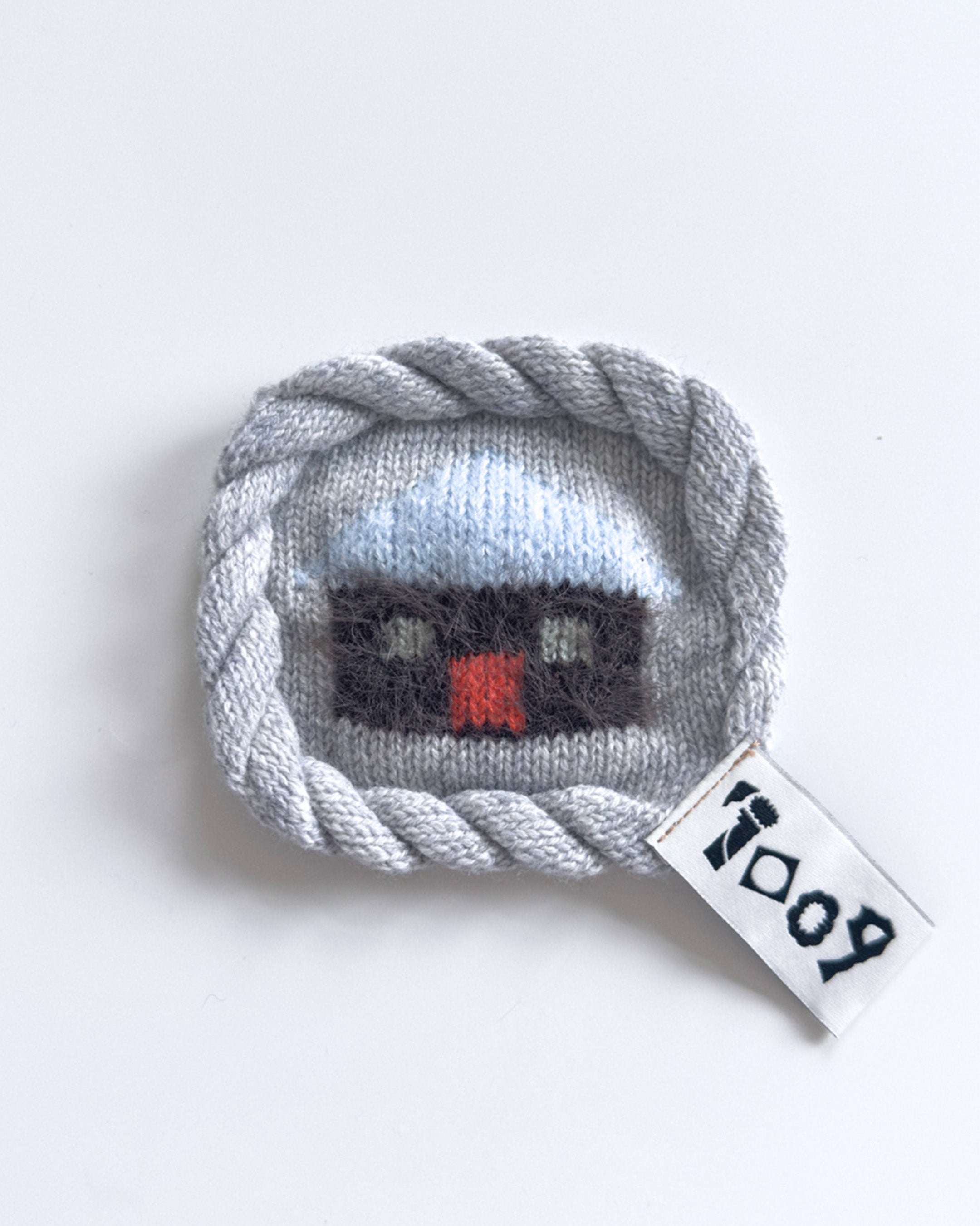 knit house coaster with colorful wool design and rope border
handmade wool coaster with house motif on white background
close-up of textured knit coaster with house pattern