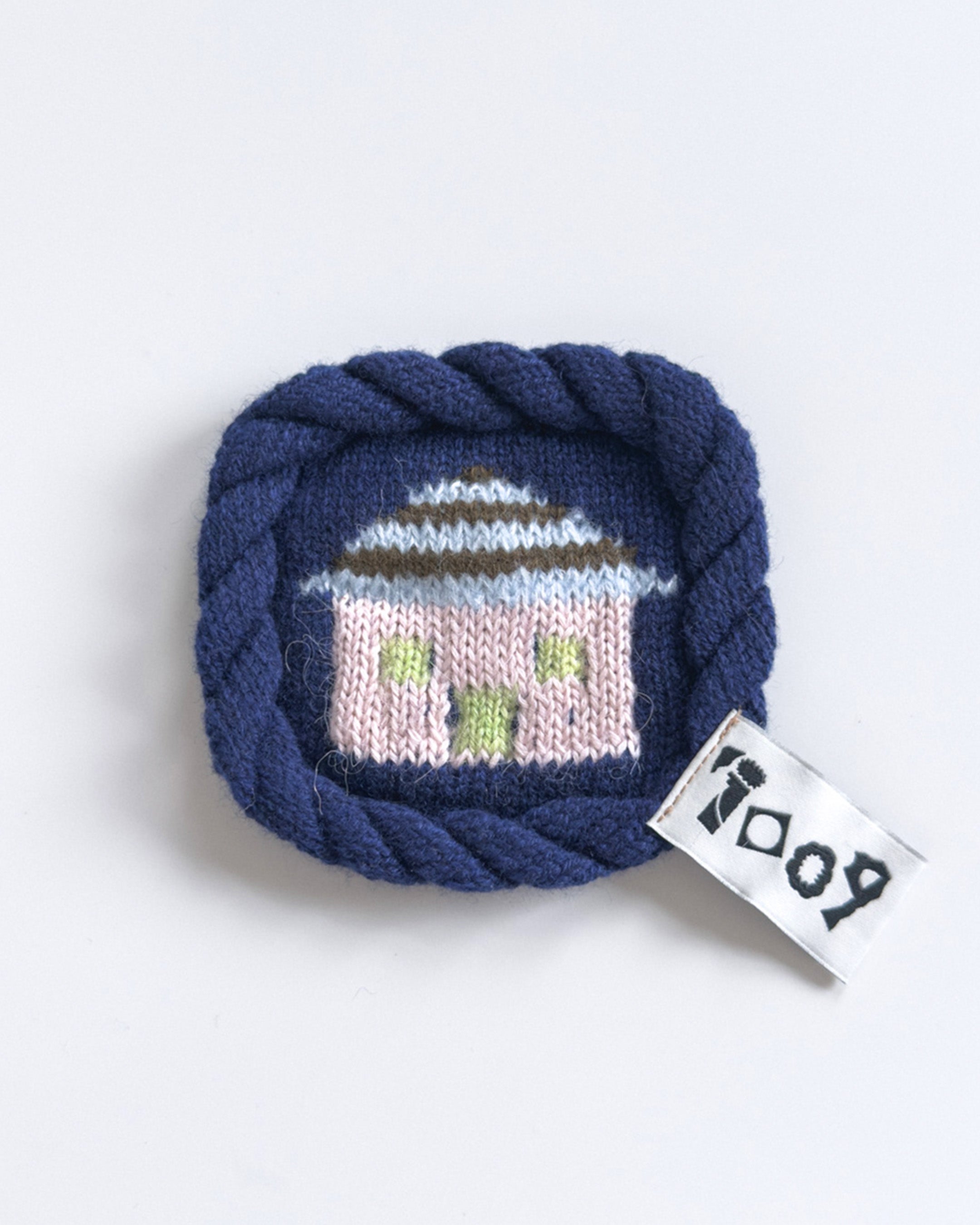knit house coaster with colorful wool design and rope border
handmade wool coaster with house motif on white background
close-up of textured knit coaster with house pattern
