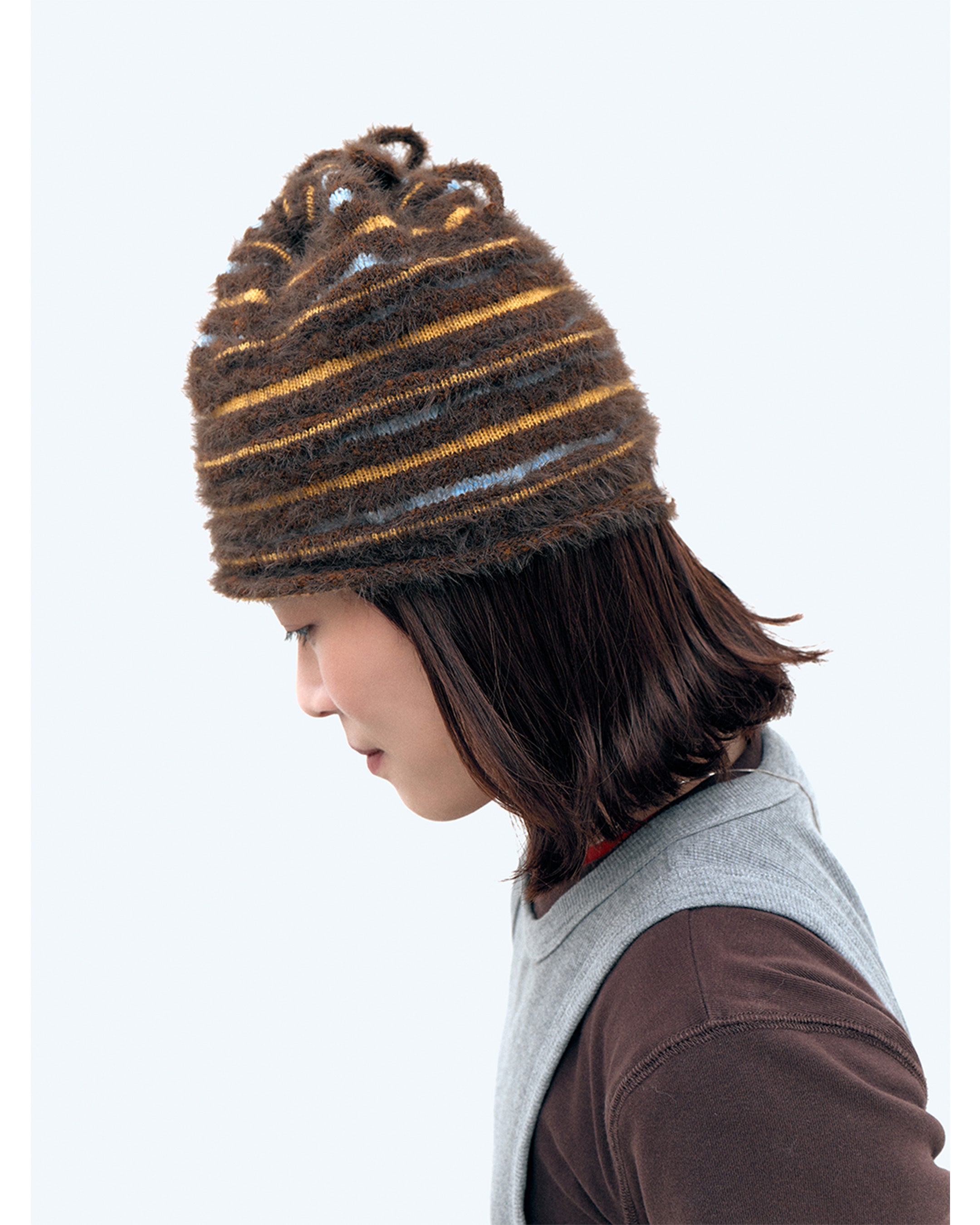 3d knit beanie with textured pattern worn on model
close-up of reversible knit beanie in brown and yellow stripes
side profile of wool mohair beanie with sculptural texture